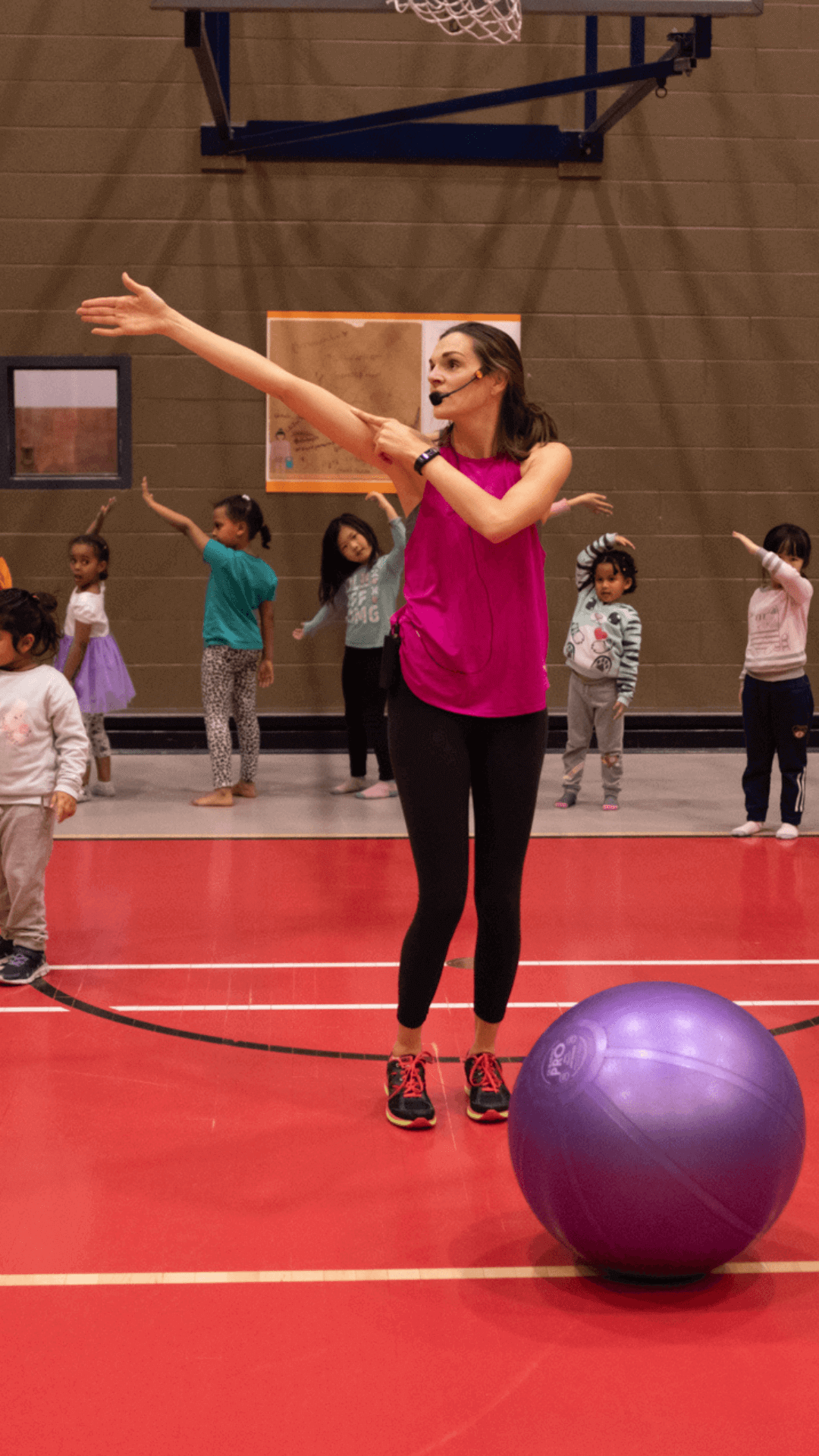 A fitness instructor teaching a class of children to dance.